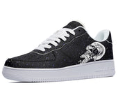 A black sneaker with a white sole and white laces. The body of the shoe has an astronaut floating in space printed on it. The astronaut is wearing a spacesuit with a helmet and is surrounded by stars and planets.