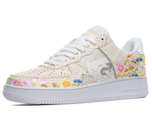 A white sneaker with a floral pattern of pink, yellow, and blue flowers on the upper and white sole. The design also incorporates text in different languages.