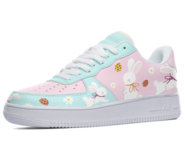 A pair of shoes with a custom design. The shoes are light blue and pink with a pattern of white rabbits, blue flowers, and pink eggs.