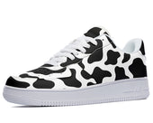 A black and white cow print sneaker with white laces and a white sole.