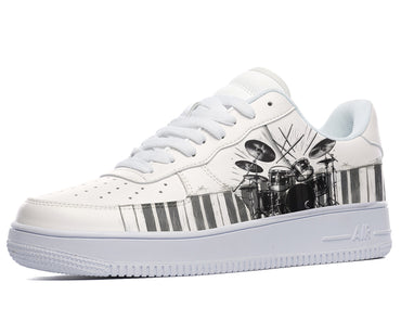 White sneakers with a black and white illustration of a drum set on the side, with piano keys at the bottom of the design. 