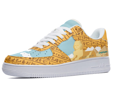 A close-up of a sneaker with a design of an Egyptian pharaoh, pyramids, and hieroglyphics on the upper. The sneaker has a white midsole and a light blue outsole.