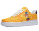 A yellow sneaker with a white sole, white laces, and a colorful pattern of diamonds and a jester on the upper.