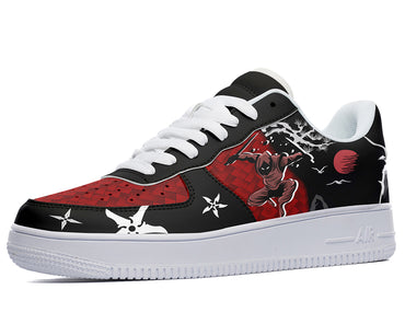 A black sneaker with a design of a ninja and a red sun on the side. The ninja is wearing a black and red outfit and is holding a sword. The sneaker has white laces and a white sole.