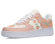 A close-up of a sneaker with a white sole and light pink upper. The upper is decorated with a colorful pattern of peaches, strawberries, and leaves.