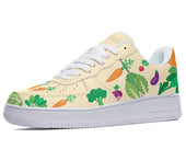 White sneakers with a cream-colored upper featuring a repeating pattern of carrots, broccoli, leafy greens, and other vegetables. 
