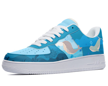 A blue sneaker with a white sole, white laces, and a design of whales, fish, and coral on the upper.