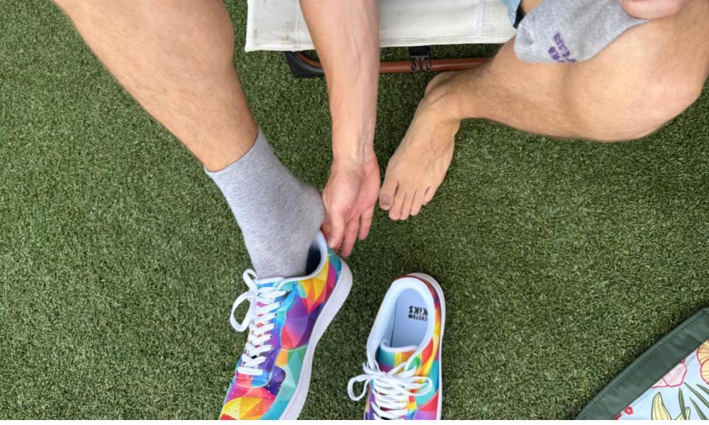 Man removing socks and  Multicolor Prism Sneakers on green grass