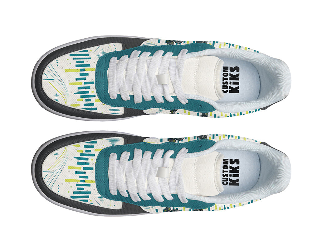 A pair of low-top sneakers shown from a top-down view on a white background. The shoes feature a white base with teal overlays, a black midsole stripe, and a colorful abstract graphic pattern in yellow, teal, and white on the toe box.
